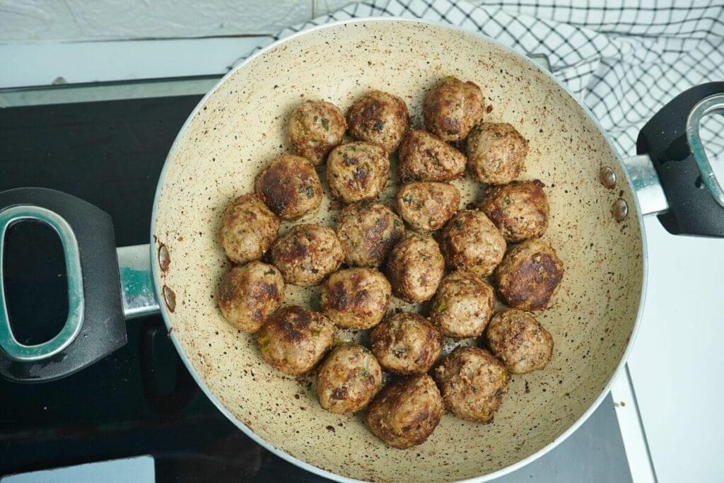 ground beef meatballs frying in pan