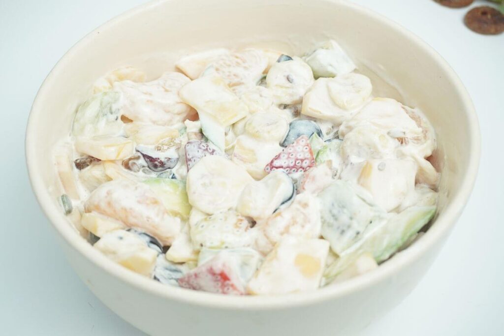 creamy fruit salad mixing all ingredints with cream